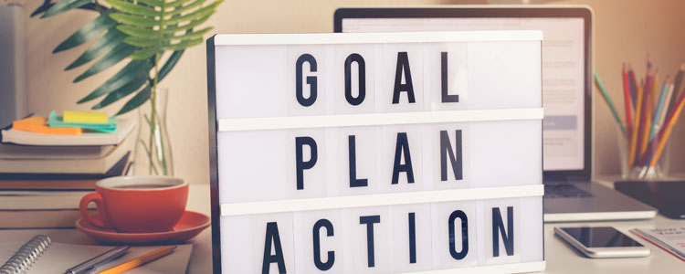 Goal, Plan, Action Sign on a desk - Using nudges to achieve your goals by Mary Guldan Lindstrom