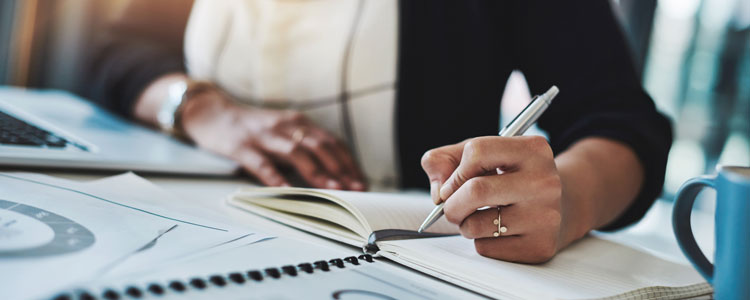 Business owner reviewing documents and taking notes - Time for a Year-End Deep Dive by Mary Guldan Lindstrom